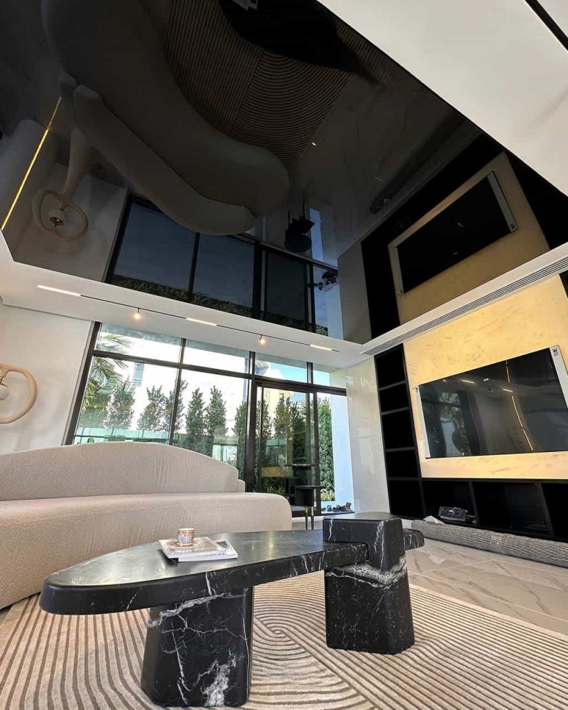 Luxury black glossy stretch ceiling with mirror reflection effect in a modern villa living room at DAMAC Hills. Luxury black glossy stretch ceiling with mirror reflection effect in a modern villa living room at DAMAC Hills.