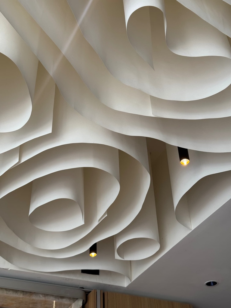 Close-up of the custom architectural fabric ceiling showcasing smooth curves, layered sculptural elements, and precision craftsmanship. The elegant design demonstrates how fabric ceilings can create unique three-dimensional architectural features for premium interiors. Close-up of the custom architectural fabric ceiling showcasing smooth curves, layered sculptural elements, and precision craftsmanship. The elegant design demonstrates how fabric ceilings can create unique three-dimensional architectural features for premium interiors.