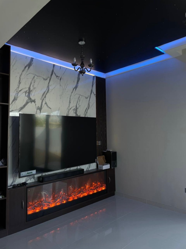 Luxury black stretch ceiling with integrated star lighting and purple RGBW perimeter illumination installed in a modern villa living room at DAMAC Hills 2 Dubai. The ceiling creates an elegant night sky atmosphere with premium ambient lighting. Luxury black stretch ceiling with integrated star lighting and purple RGBW perimeter illumination installed in a modern villa living room at DAMAC Hills 2 Dubai. The ceiling creates an elegant night sky atmosphere with premium ambient lighting.