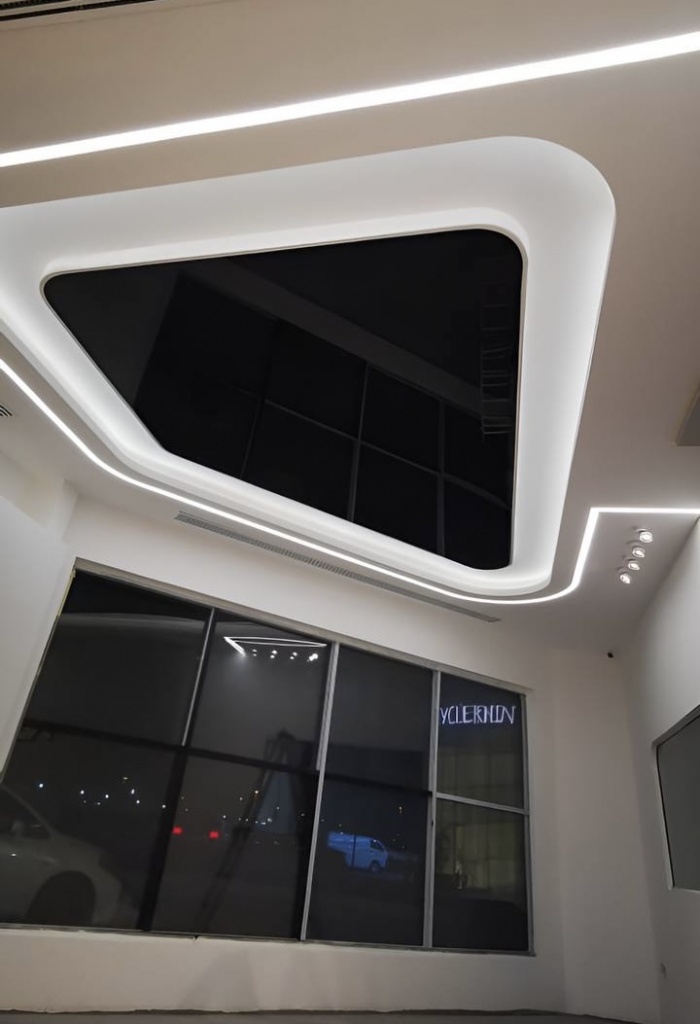 Custom black reflective stretch ceiling with rounded geometry and seamless recessed installation in a premium Tesla service facility. Custom black reflective stretch ceiling with rounded geometry and seamless recessed installation in a premium Tesla service facility.