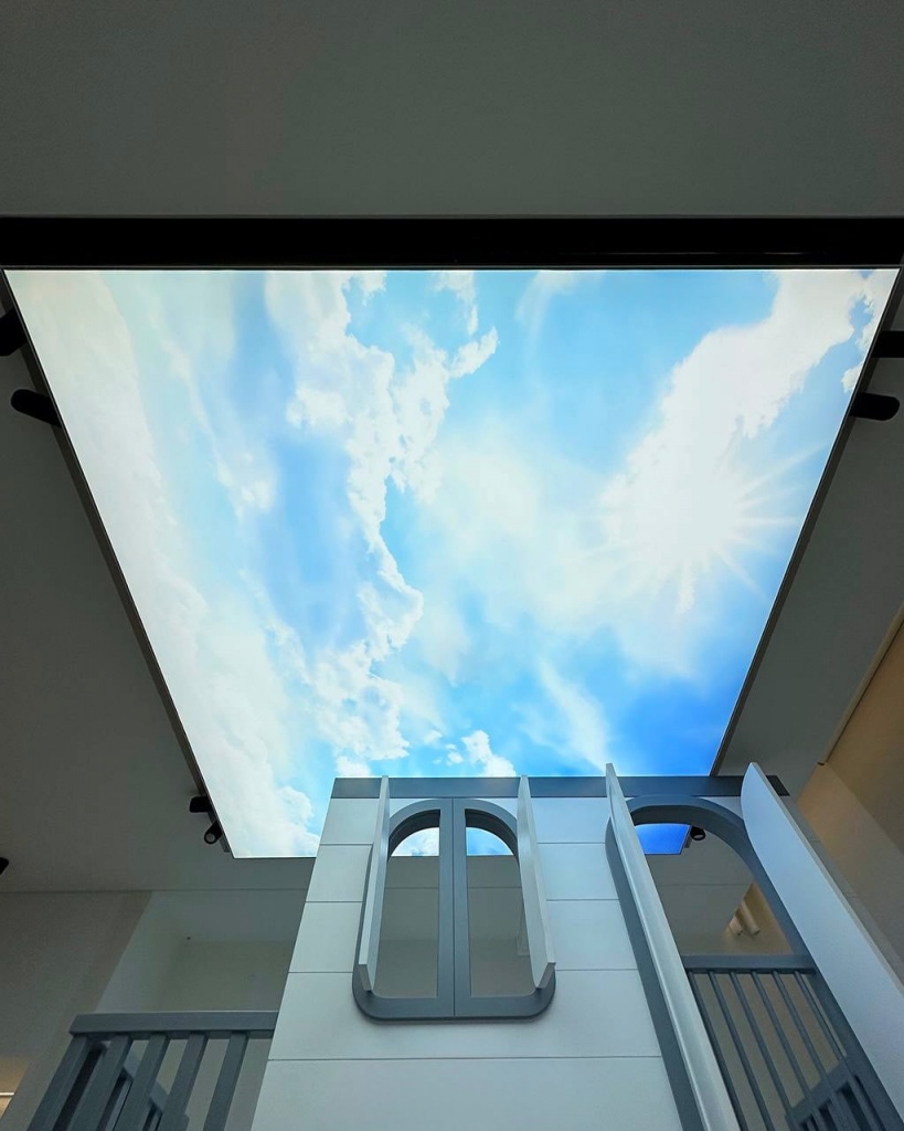 Modern 3D illuminated stretch ceiling with black architectural divisions and seamless LED illumination in a Dubai commercial space. Modern 3D illuminated stretch ceiling with black architectural divisions and seamless LED illumination in a Dubai commercial space.