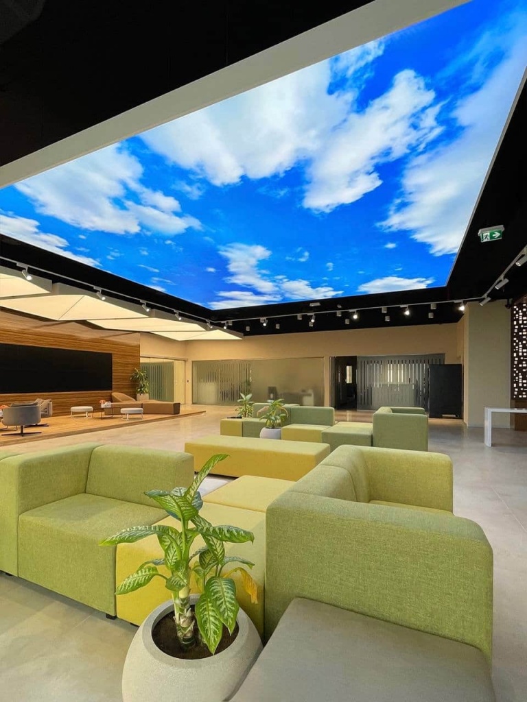 Custom translucent stretch ceiling with illuminated cloud print creating a bright and visually open commercial interior space. Custom translucent stretch ceiling with illuminated cloud print creating a bright and visually open commercial interior space.