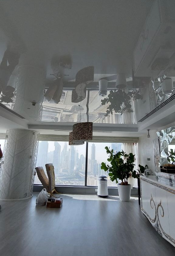 Luxury white glossy stretch ceiling with mirror reflection effect in a modern apartment interior in central Dubai. Luxury white glossy stretch ceiling with mirror reflection effect in a modern apartment interior in central Dubai.