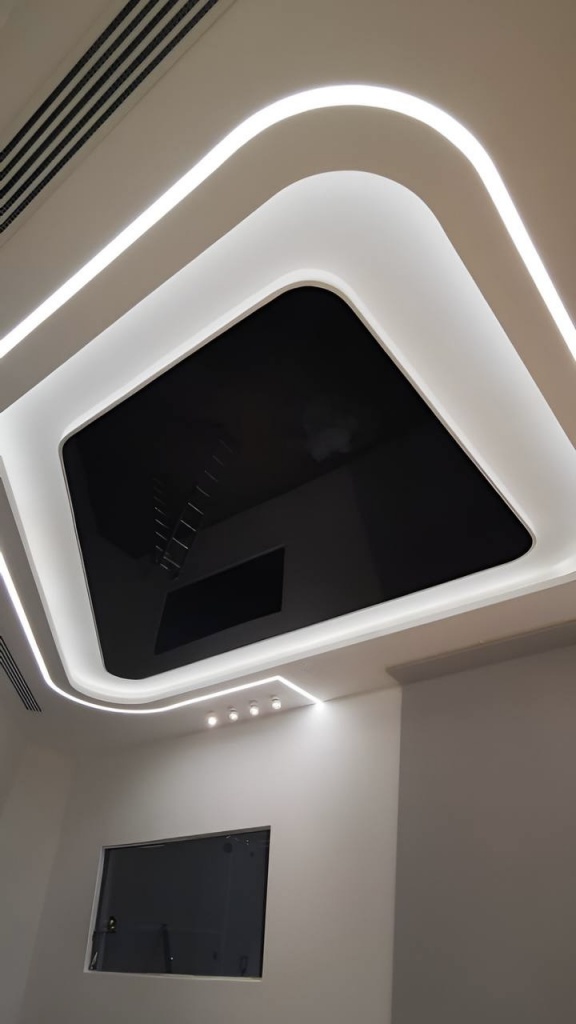 Black glossy stretch ceiling with curved recessed LED lighting installed in the Tesla Service Center in Dubai International City. Black glossy stretch ceiling with curved recessed LED lighting installed in the Tesla Service Center in Dubai International City.