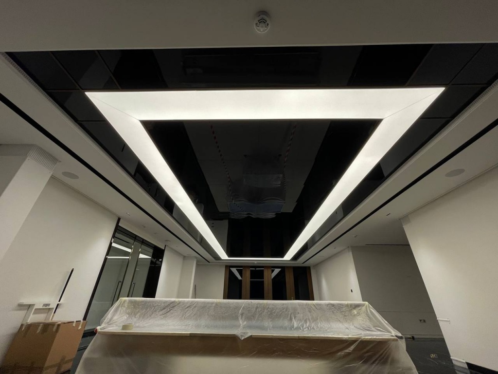 Modern black gloss ceiling with mirror reflections and integrated architectural light box lighting in a premium residential interior. Modern black gloss ceiling with mirror reflections and integrated architectural light box lighting in a premium residential interior.
