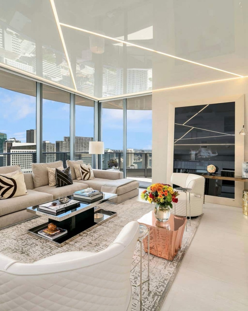 Minimalist living room featuring a seamless reflective stretch ceiling with architectural lighting. Minimalist living room featuring a seamless reflective stretch ceiling with architectural lighting.