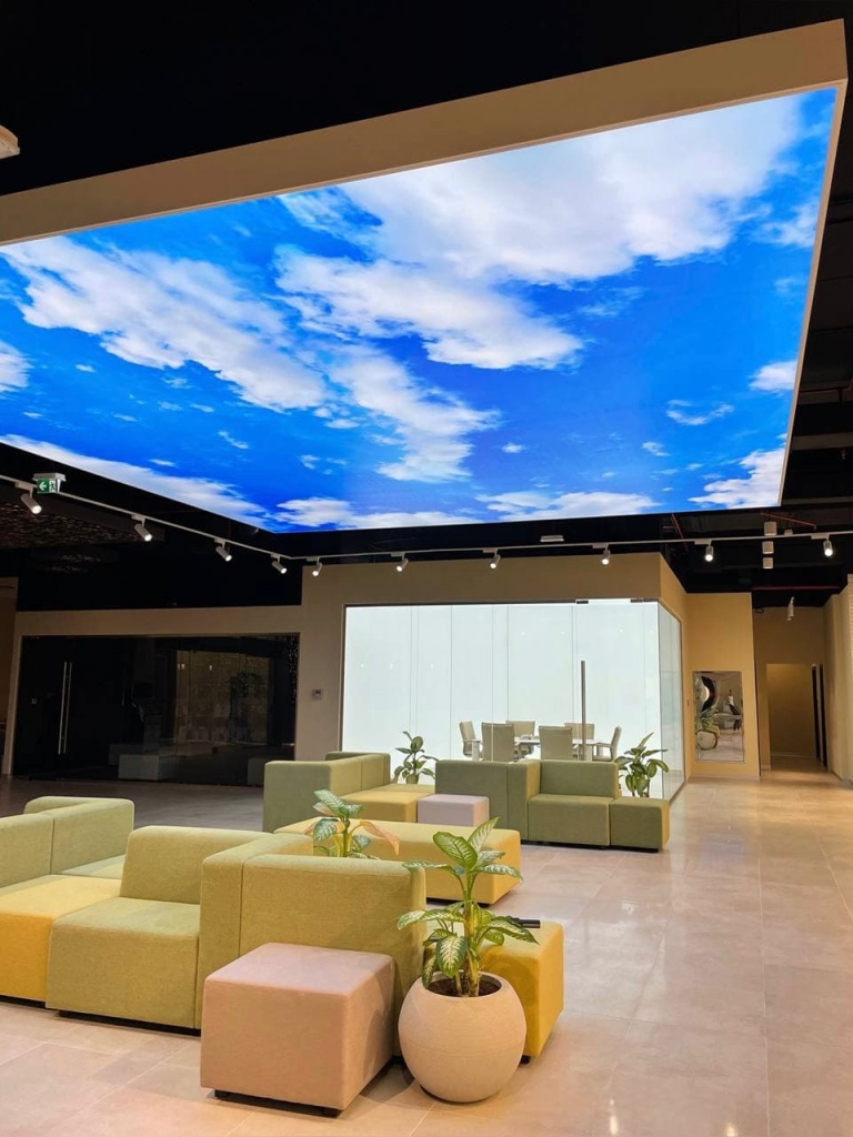 Modern floating lightbox ceiling with integrated LED illumination and sky image print for a contemporary office lounge area. Modern floating lightbox ceiling with integrated LED illumination and sky image print for a contemporary office lounge area.